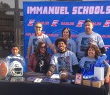 Immanuel High School standout football player Winston Williams (center), flanked by friends and family, signs a letter-of-intent to attend UC Davis to play football.